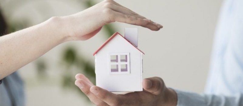 close-up-hands-protecting-small-house-model_23-2148204008